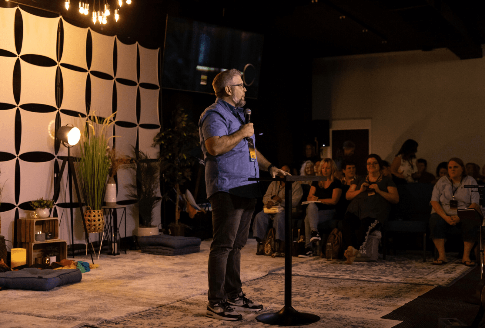 Dr. Joshua Todd speaking on stage with artistic backdrop